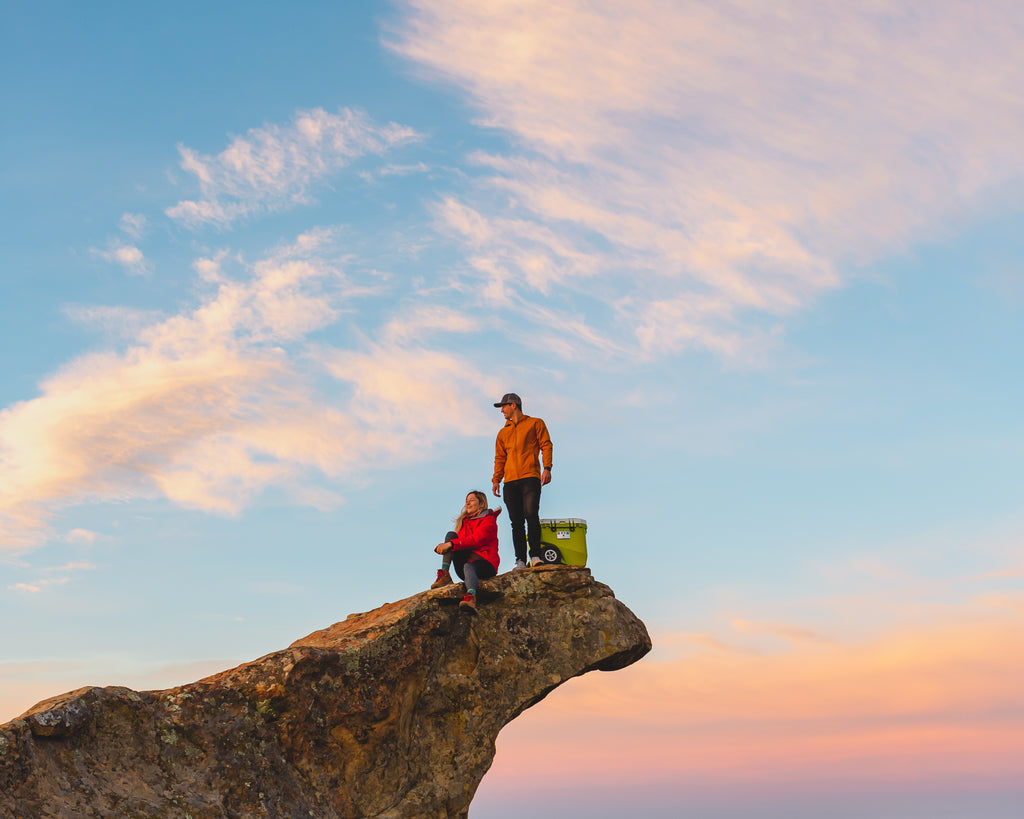 Couple sits on top of the mountains with their RollR at sunset.